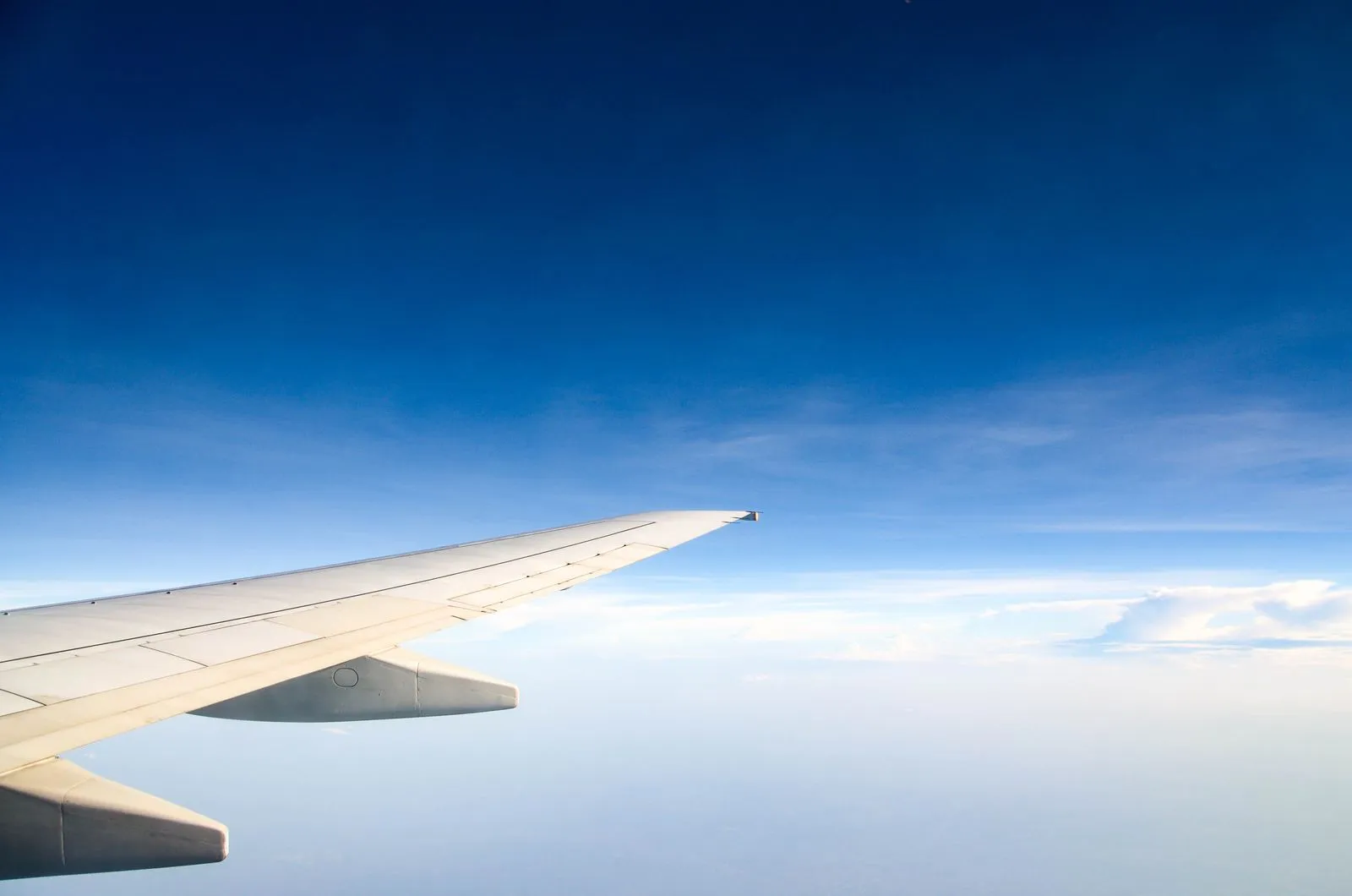 Airplane wing above clouds during flight, illustrative photo of commercial air travel
